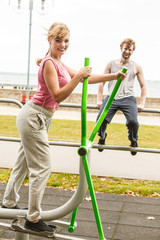 Man and woman exercising on elliptical trainer.