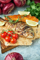 Grilled dorado fish and salmon steak on a wooden board 