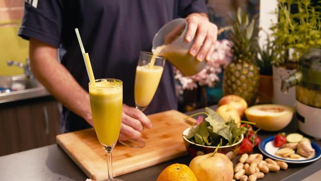 Hands pouring fresh vegan juice in a glass to drink