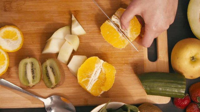 Slicing fruits for vegan smoothie with apple  orange and knife