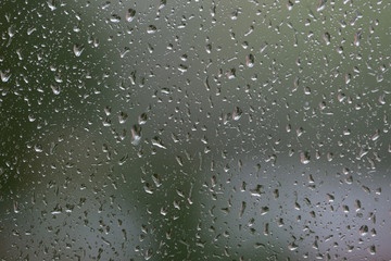 Raindrops on window glass during the rain close up. Natural background