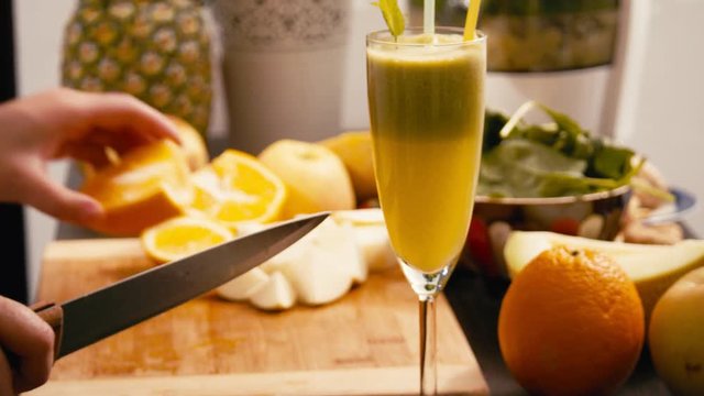 Slicing fruits for vegan smoothie with apple  oranges and knife
