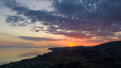 Aerial photography. Evening view of the sea and shore. Sunset over the water. Clouds in the sky.