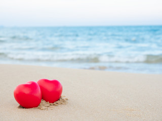 Two heart shape put on the sand at the beach and blue sea blurred background. Valentines day concept,love, married