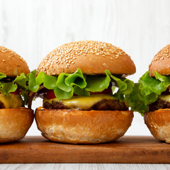 Homemade cheeseburgers on rustic wooden board, side view. Closeup.