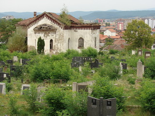 Zarośnięty zielenią cmentarz serbski w Kosowskiej Mitrowicy w Kosowie, zrujnowana kaplica cmentarna