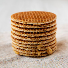 Stack of homemade Dutch stroopwafels with honey-caramel filling on cloth, low angle view. Close-up.