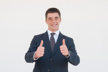 Cheerful young professional expressing approval. Young man in office jacket and tie showing thumbs up and smiling at camera. Like gesture or approval concept