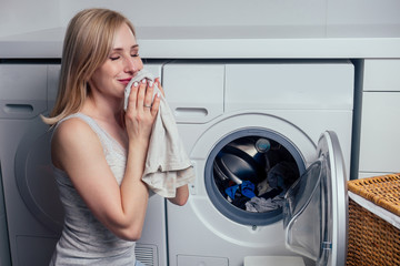 happy blonde female washing clothes feeling happy about soft fresh laundry aroma fabric softener...