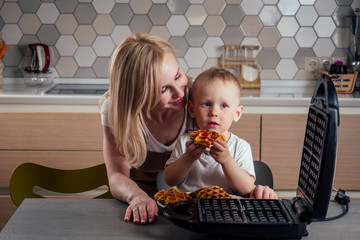 caucasian family together cooking kitchen.boy and mother eating Belgian waffles waffle iron