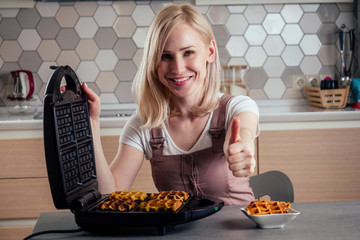 Woman taking fresh wafers out of waffle iron in kitchen Belgian waffles