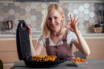Woman taking fresh wafers out of waffle iron in kitchen Belgian waffles