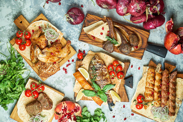 Plates of meat with barbecue and kebab, top view on gray background