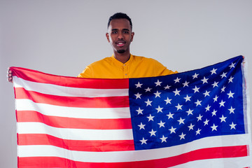 african american man looking at camera and proudly holding american flag at studio