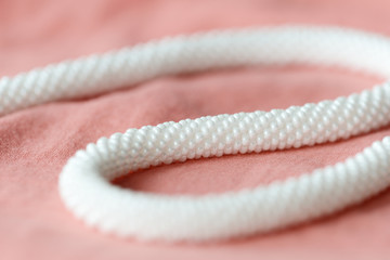 White beaded necklace on a textile background coral color close up