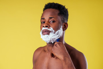 African-american man with razor and shaving foam on his face