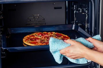 woman openung ovens and take pizza with tomatoes, olives, mushrooms and cheese sausage