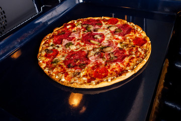 woman openung ovens and take pizza with tomatoes, olives, mushrooms and cheese sausage