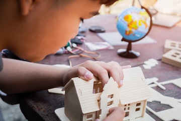 Asian boy building toy house or jigsaw home at outdoor near globe, making construction from small details, design from learn programming process of robot technology / STEM education. Learning by doing