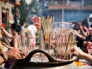 Hands stab Incense sticks on joss stick pot burning and smoke used to pay respect to Buddha.
