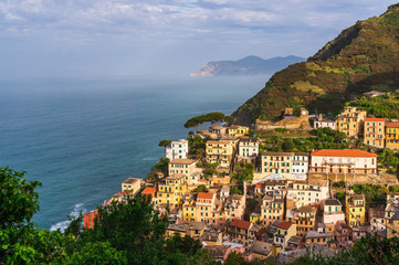 Obraz premium The picturesque village of Riomaggiore, Cinque Terre, Italy, on a lovely summer morning. Old traditional and colorful Italian terraced houses built at the seaside in a valley surrounded by mountains.