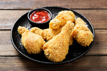 Crispy  fried chicken drumsticks  in a wooden table.