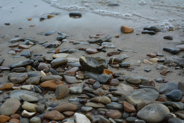 Pebble stones on the sandy shore of river. Closeup.