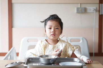 Asian child patient or kid girl Influenza A sick and sad with cry to want encouragement with salt water in hand blood vessels on bed at hospital room for treatment healthcare with lunch food