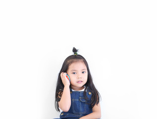 Asian child cute or kid girl smiling and playing smartphone toy or talking on mobile phone for communication learning or call and wear dungarees jean on white background isolated with space