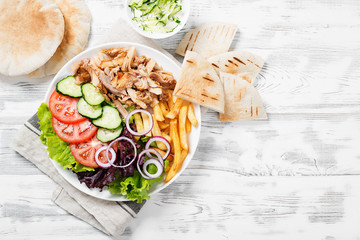 Doner kebab or gyros on a plate with french fries, pita bread and salad.