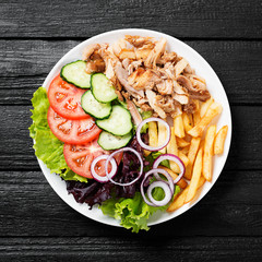 Doner kebab or gyros on a plate with french fries, pita bread and salad.