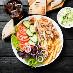 Doner kebab or gyros on a plate with french fries, pita bread and salad.