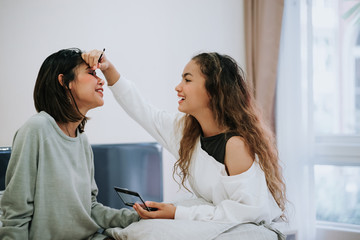 Happy Family teenage daughter is makeup to the mother in the bedroom in the morning before working.