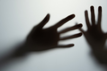 shadow hands of the man behind frosted glass. blurry hand abstraction halloween, silhouette of a hand blur shadow of a blurry hand behind the glass.