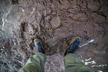legs in army boots in wet mud closeup top-down vew with selective focus at daylight