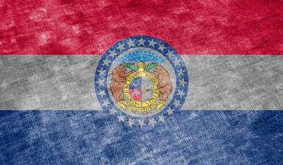 The national flag of the US state Missouri in against a gray textile rag on the day of independence in different colors of blue red and yellow. Political and religious disputes, customs and delivery.