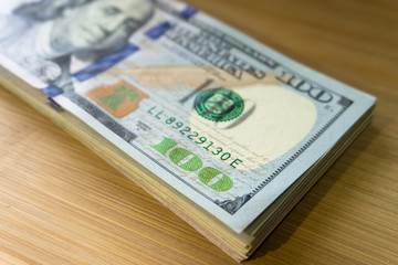 crolled stack of 100 new dollar bills on wooden background