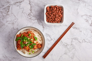 shan noodles with peanuts and chopsticks at white marble tabletop. burmese cuisine traditional dish. myanmar food. rice noodles with pork in tomatos