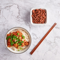 shan noodles with peanuts and chopsticks at white marble tabletop. burmese cuisine traditional dish. myanmar food. rice noodles with pork in tomatos. top view. square