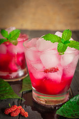 Fresh Ice Mulberry Soda drink on the wood table there are Mulberry, Leaves and same object placed around.