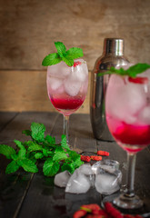 Fresh Ice Mulberry Soda drink on the wood table there are Mulberry, Leaves, Ice, cocktail shaker and same object placed around.