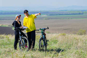 Obraz premium Cyclists man and woman are away from the city. A man points the way with his finger.