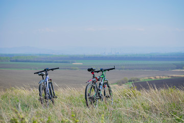 Obraz premium Two mountain bikes stand on a hill. Away industrial city.