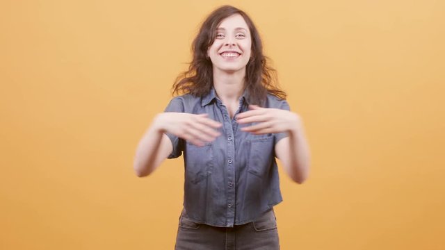Young woman is greatful and thankful to the audience. Portrait of an actress receiving ovations over yellow background.