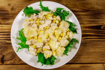 Festive salad with chicken breast, sweet corn, canned pineapple and mayonnaise on wooden table