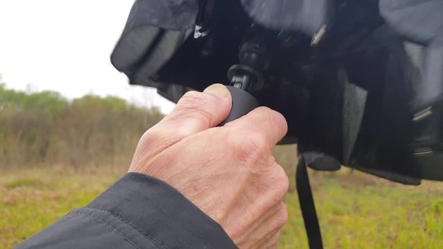 A man opens an umbrella slow motion. Click on the umbrella button to open it.