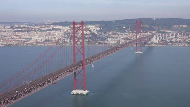 The Bridge of 25th April with car traffic and panoramic view of the city on the background, Lisbon, Portugal, 4k