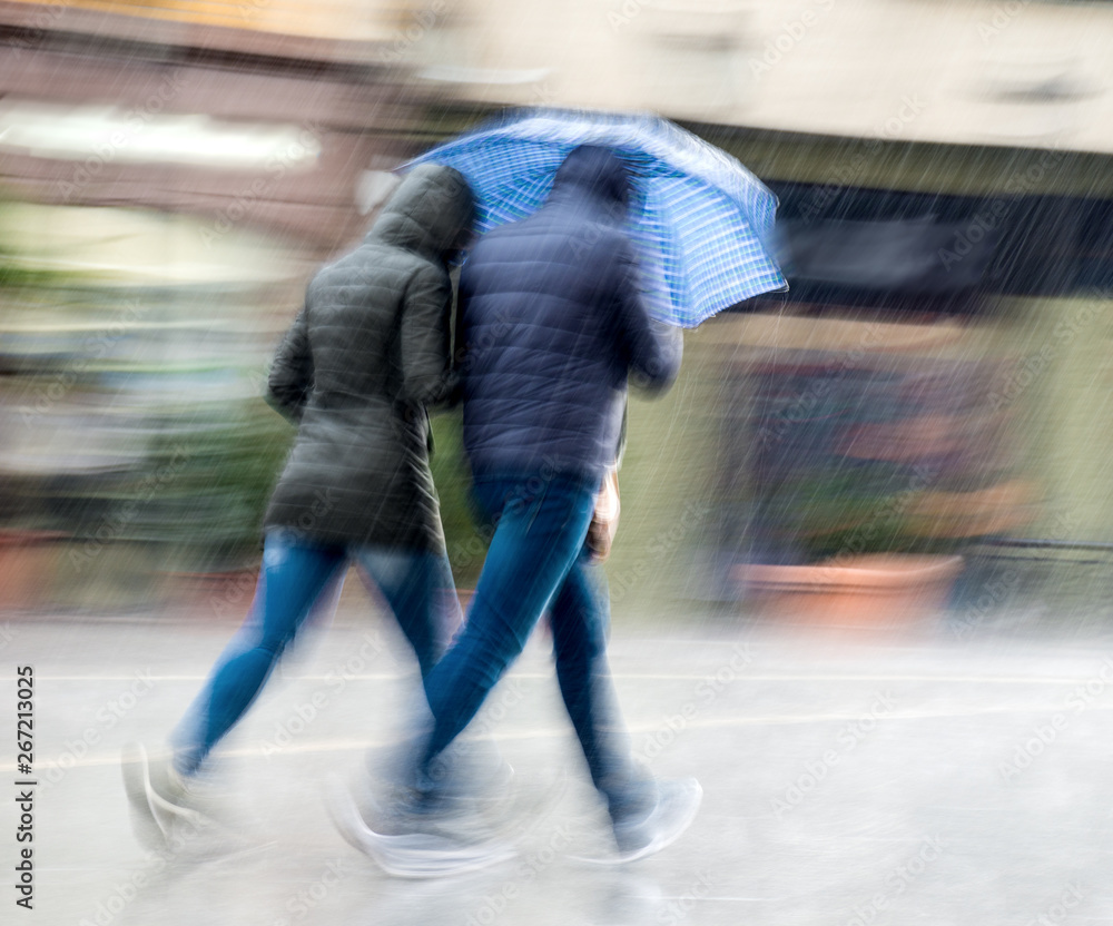 Wall mural people with umbrella walking down the street on rainy day