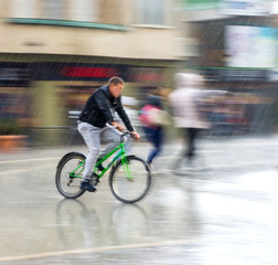 Fototapeta na wymiar Cyclist on the city roadway in motion blur in rainy day. Intentional motion blur