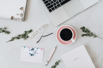 Minimal home office desk workspace with laptop, coffee, notebook, eucalyptus, envelope. Flat lay,...